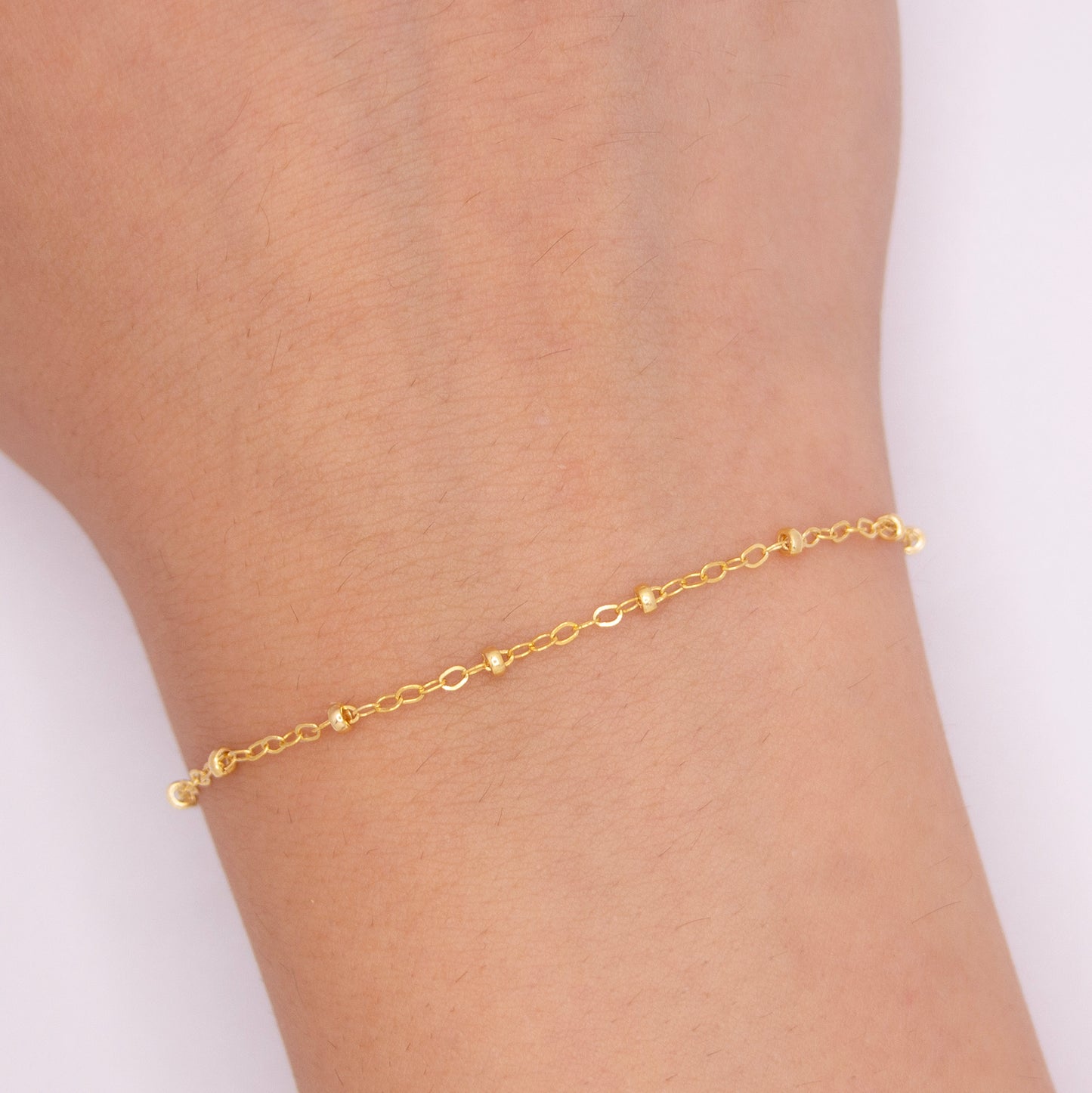 Gold filled chain with beads on a human's hands